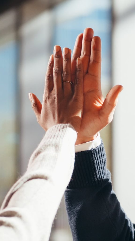 Close-up of two diverse peoples hands high-fiving in a gesture of success and teamwork.